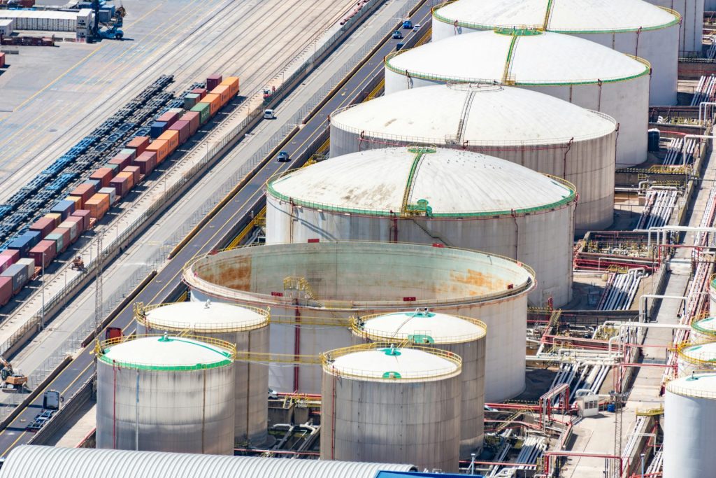 Aerial shot of large oil storage tanks in an industrial district with adjacent railway tracks.